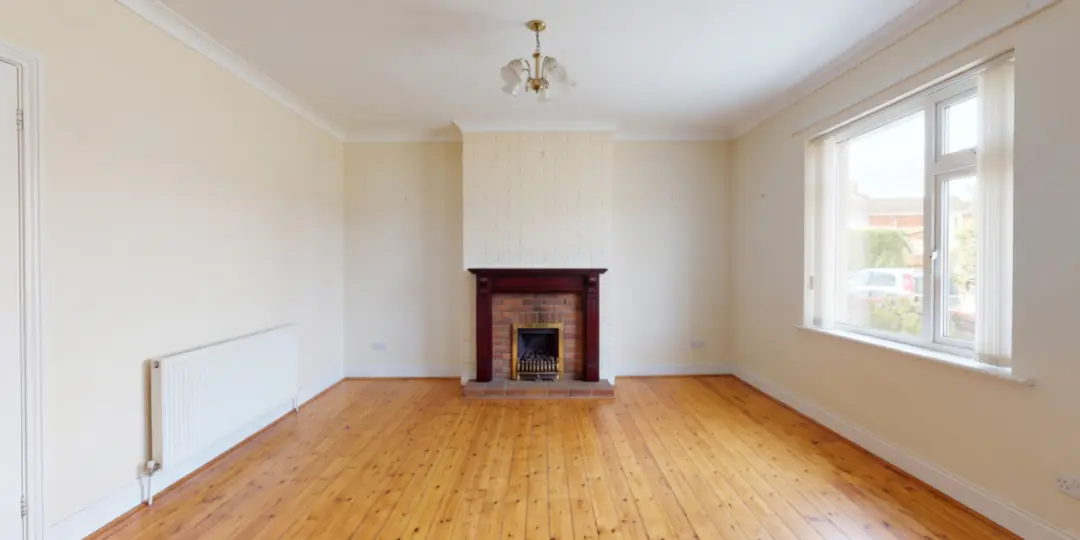 After: The same living room emptied, with its fireplace, radiator, window and ceiling light in place